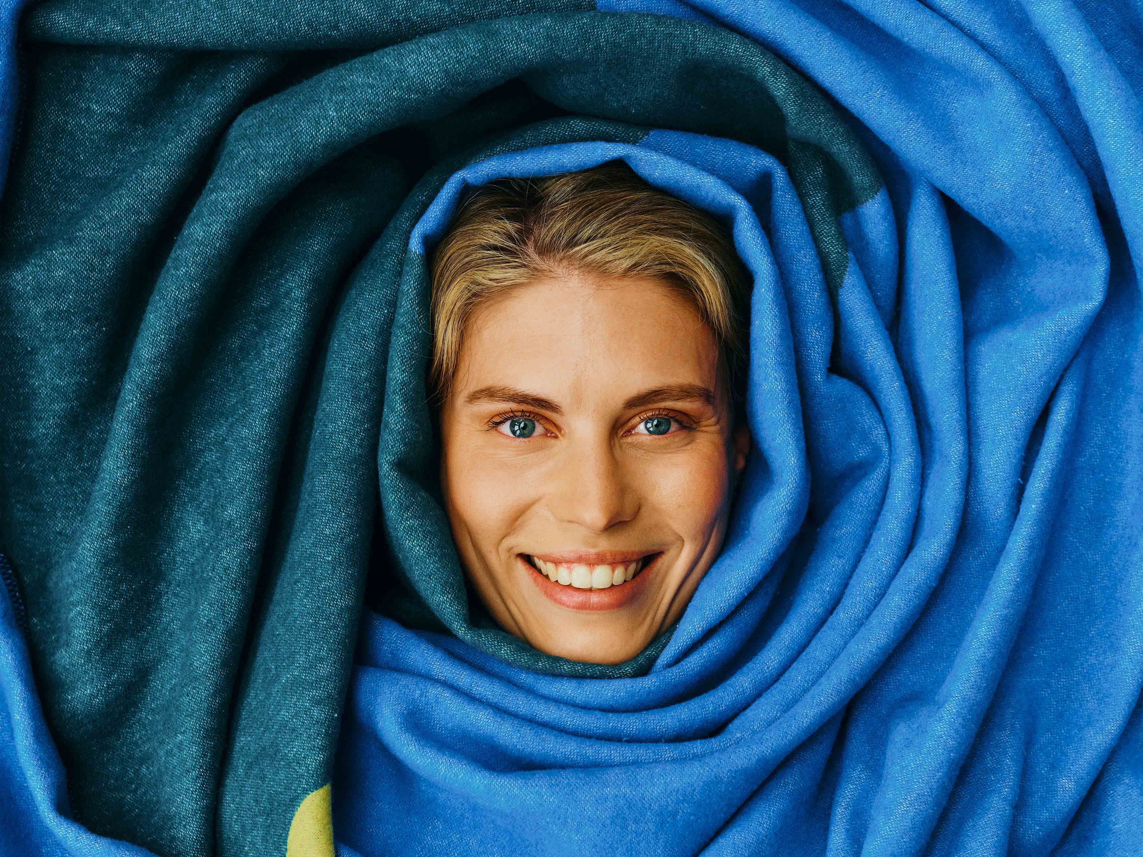 Frau ist in blauer Decke "Clemens" eingekuschelt.