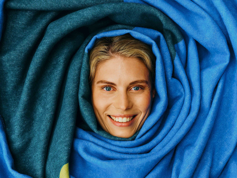 Frau ist in blauer Decke "Clemens" eingekuschelt.