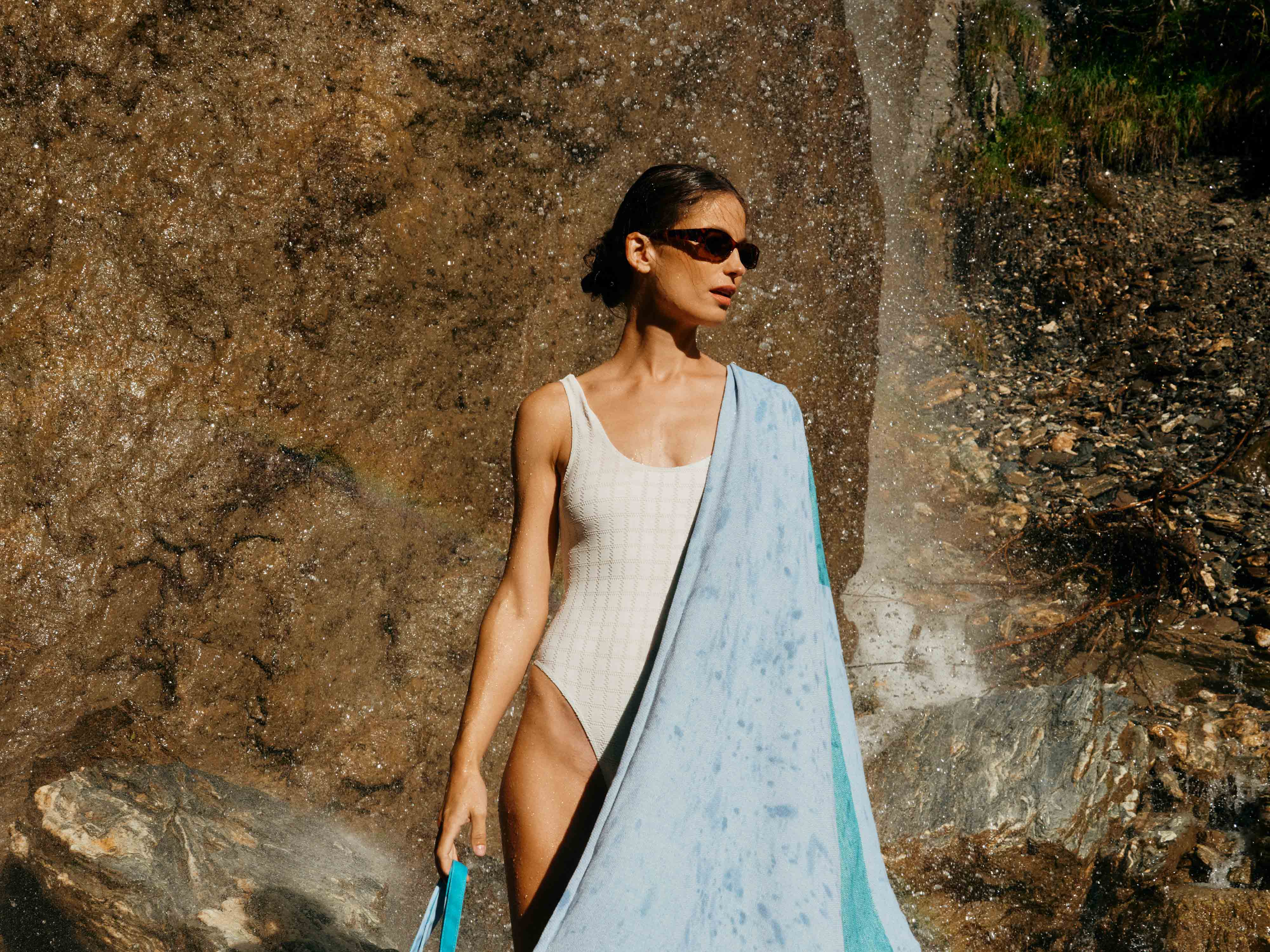 Frau im Badeanzug mit blauem Strandtuch