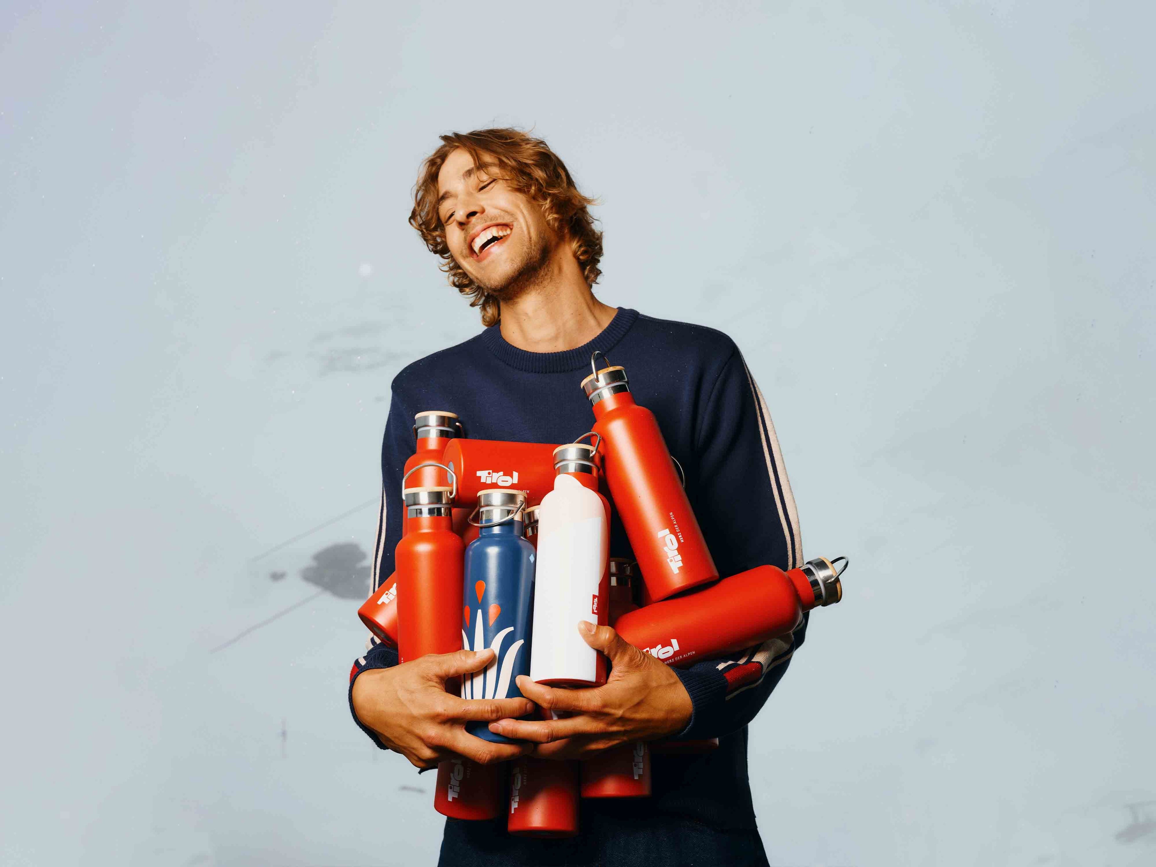 Lachender Mann mit Tirol Trinkflaschen in den Armen