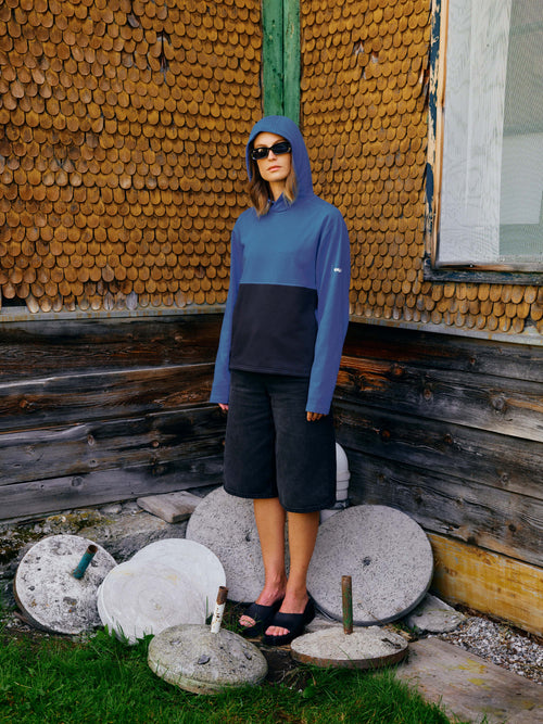 Eine Dame trägt den Unisex Hoodie "Noel" mit Kapuze und kleinem, weißem Tirol-Logo am linken Ärmel.