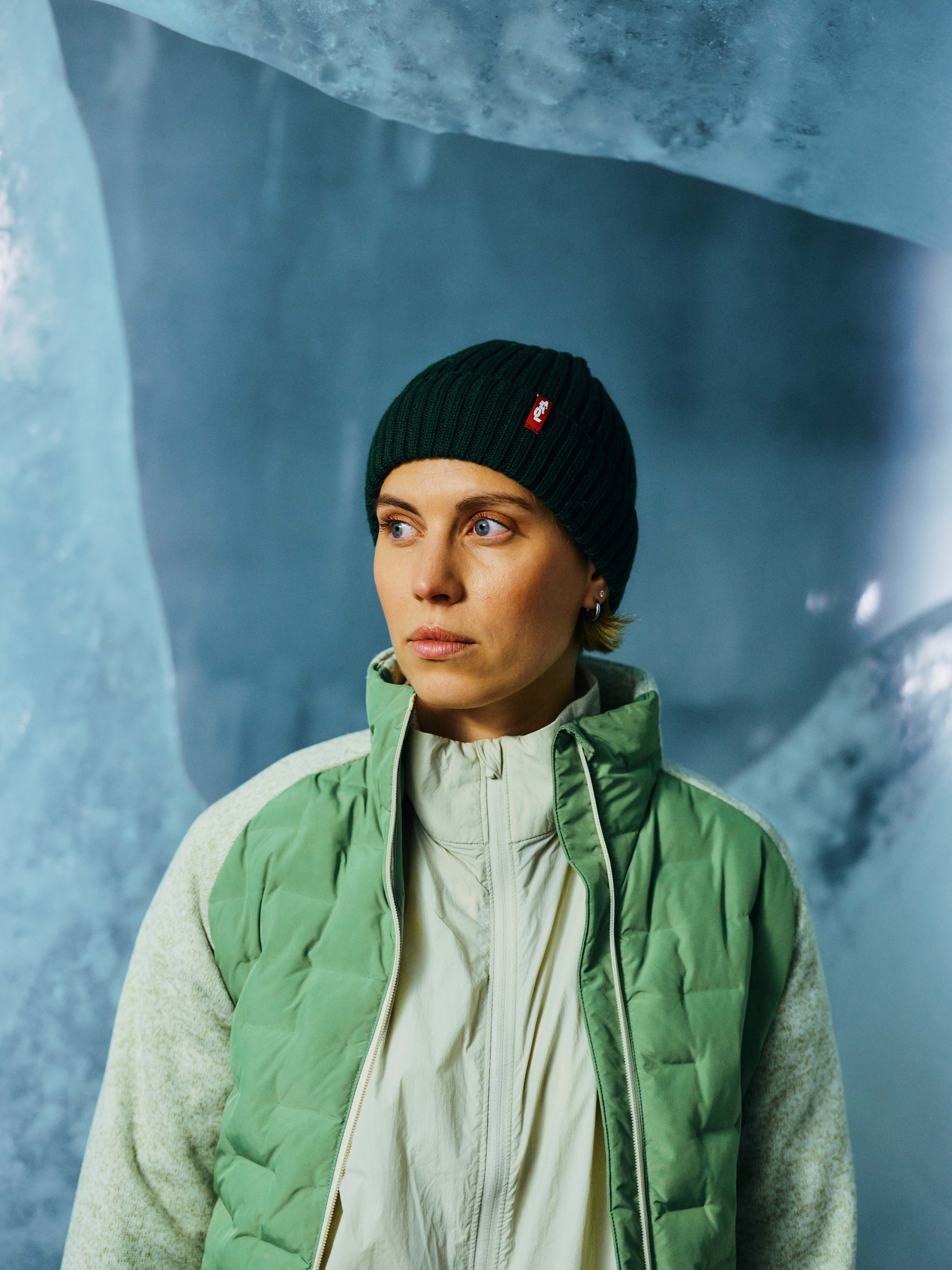 Eine Dame trägt eine dunkelgrüne Mütze in Kombination mit der Jacke "Tini".