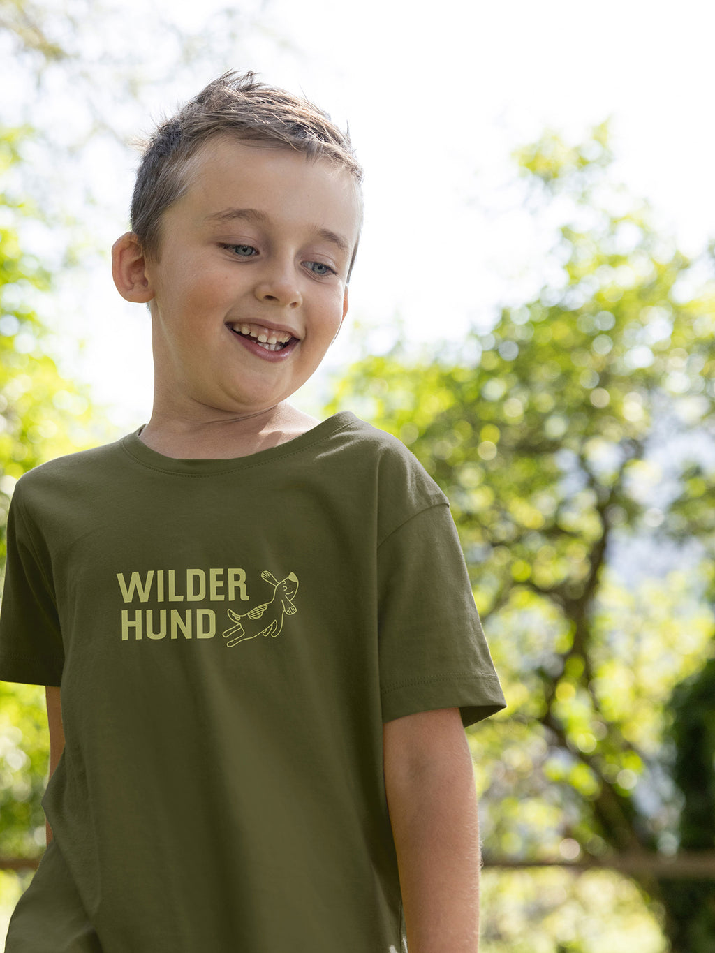 Junge trägt Tirol Shirt mit Wilder Hund Aufdruck aus Bio Baumwolle in der Farbe Olivgrün