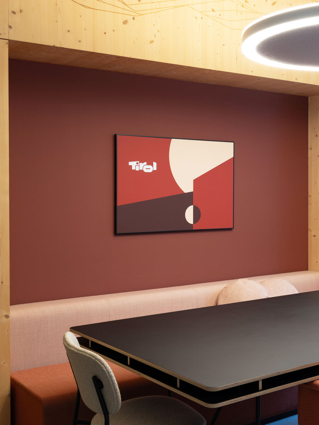 Plakat der Tirol Werbung "Tirol Logo" zum 50-jährigen Jubiläum des Tirol Logos hängt an einer dunkelroten Wand