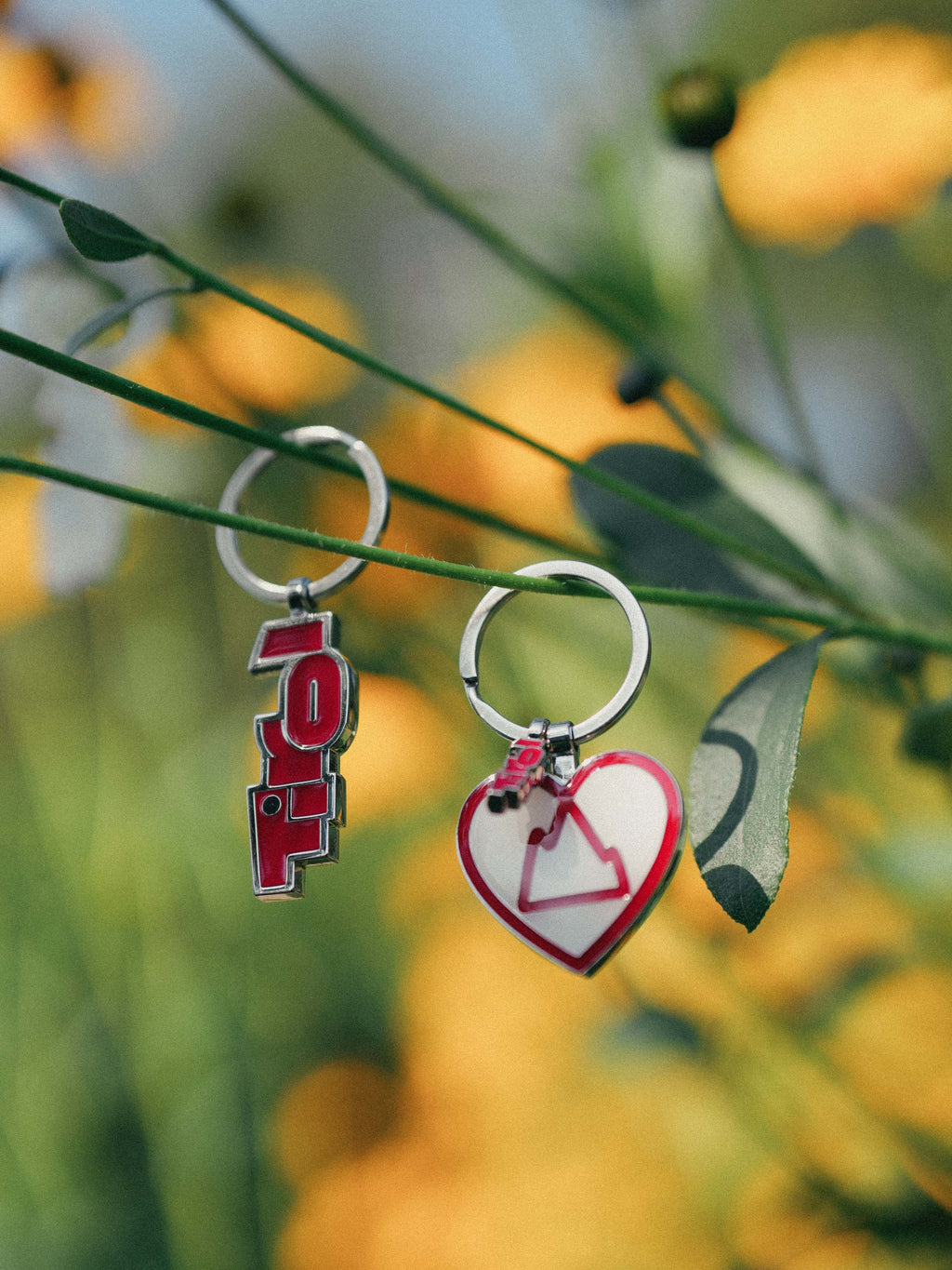 Die Schlüsselanhänger "HerzBerg" und "Tirol Logo" hängen auf einer gelben Blume