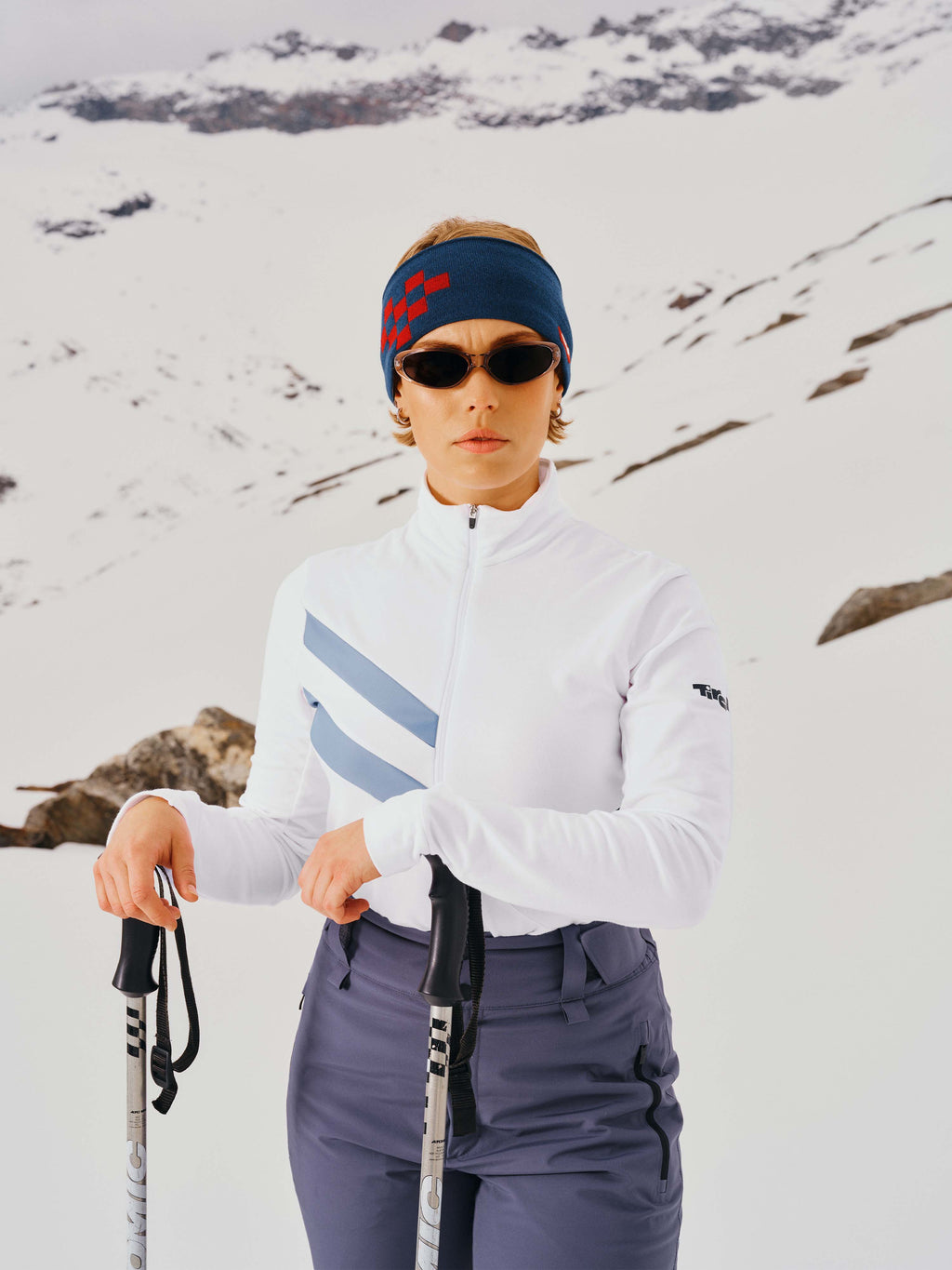 Eine Dame mit Stirnband und Sonnenbrille steht im Schnee und trägt das Sport-Longsleeve "Laura" in Weiß.
