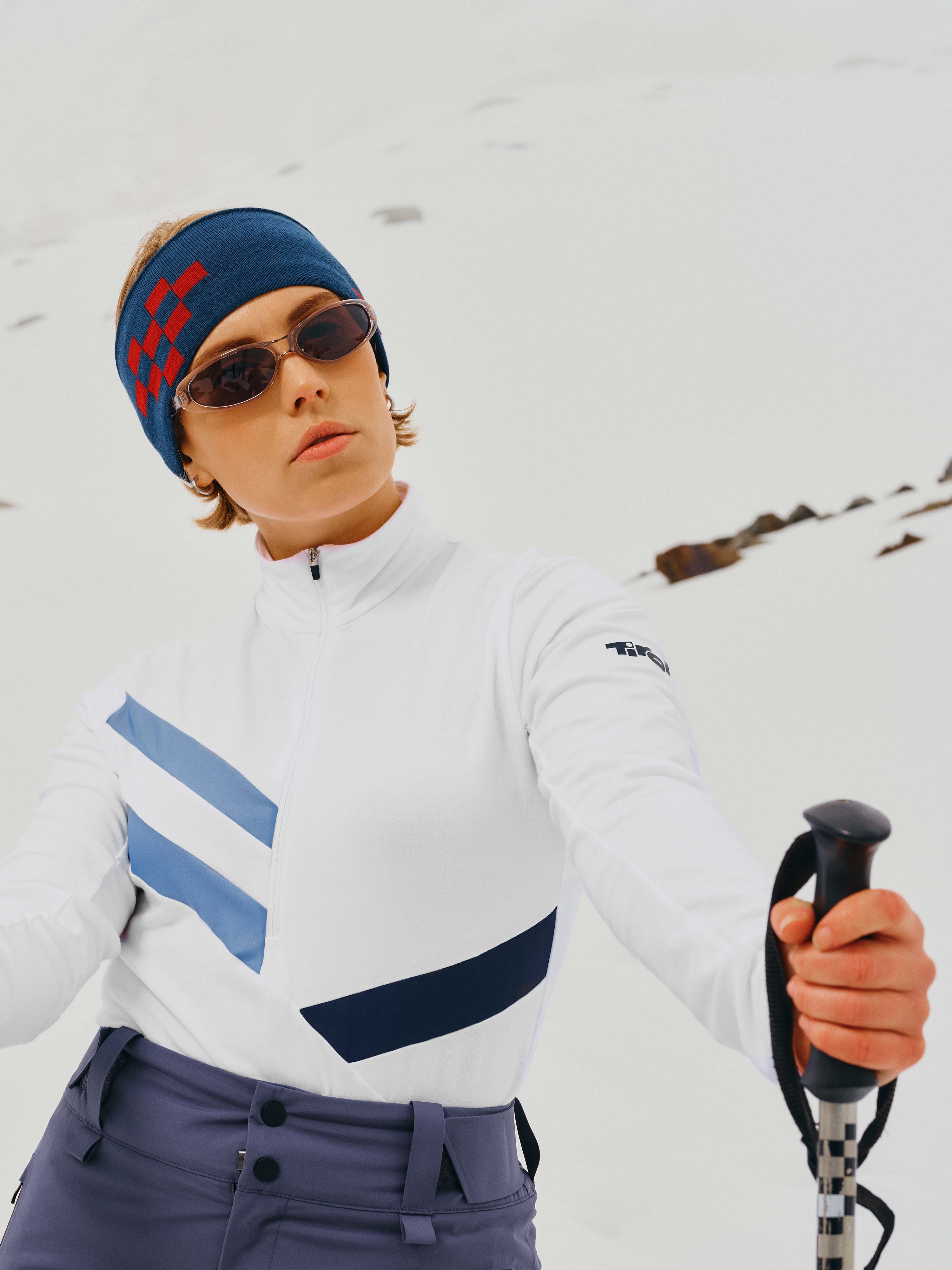 Eine Dame mit Stirnband und Sonnenbrille steht im Schnee und posiert mit dem Sport-Longsleeve "Laura" in Weiß.