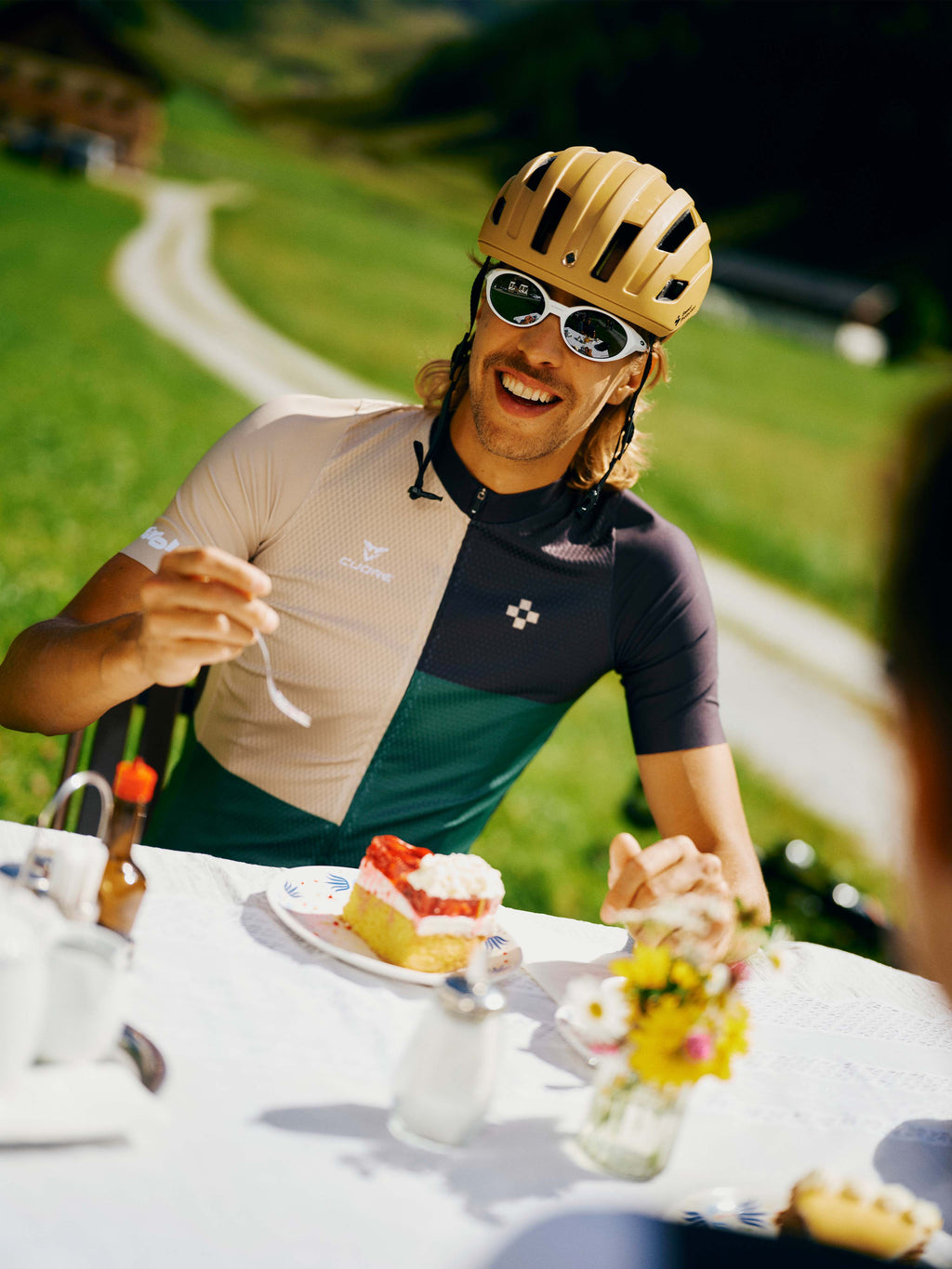 Mann trägt Rad Trikot " Timmelsjoch" in Grün bei einen Stück Kuchen