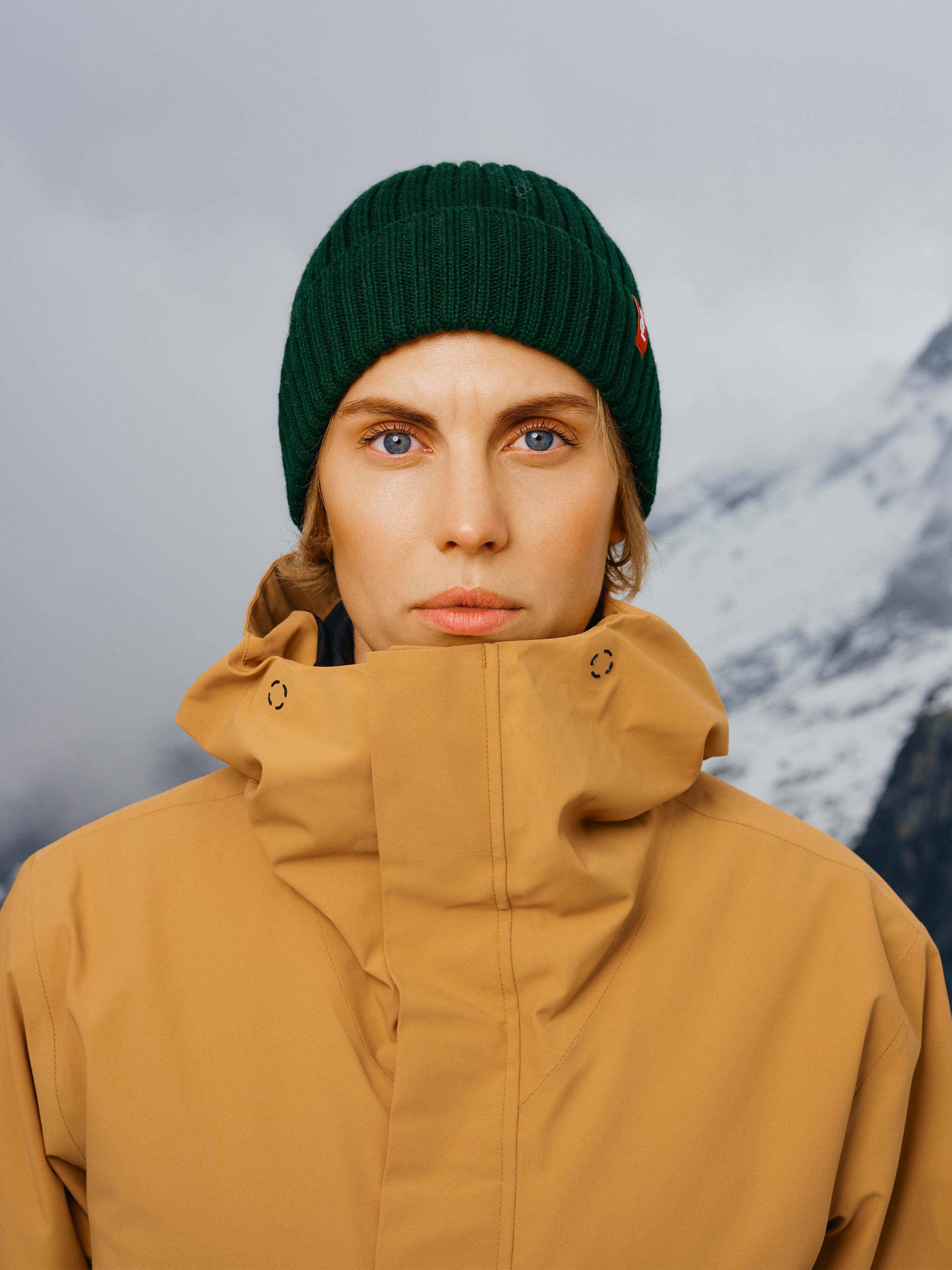 Eine Frau trägt die Winterjacke "Toni" in Kombination mit einer grünen Mütze