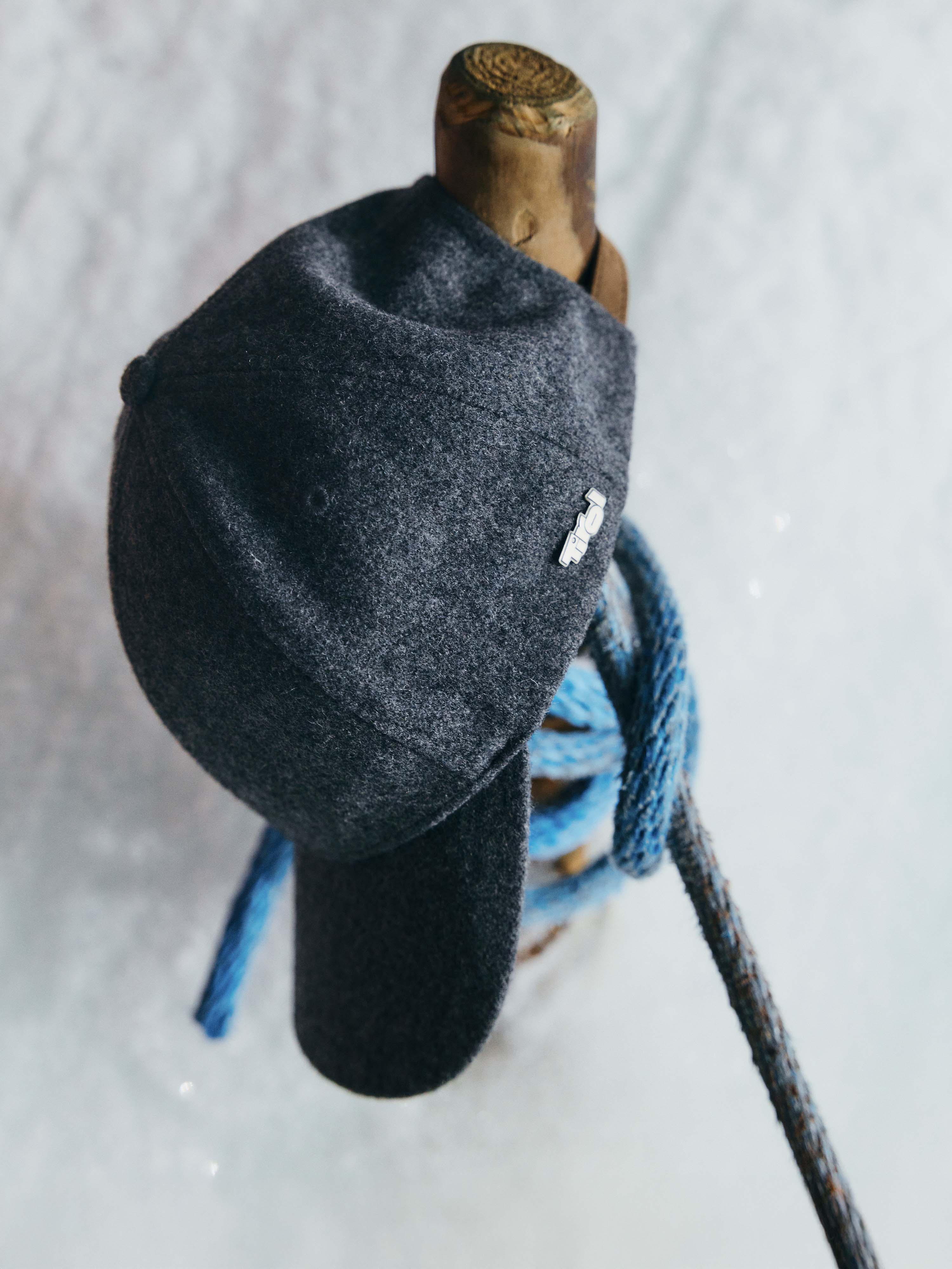 Die Unisex Wool Cap "Dani" in der Farbe Anthrazit hängt an einem Holzpfosten.